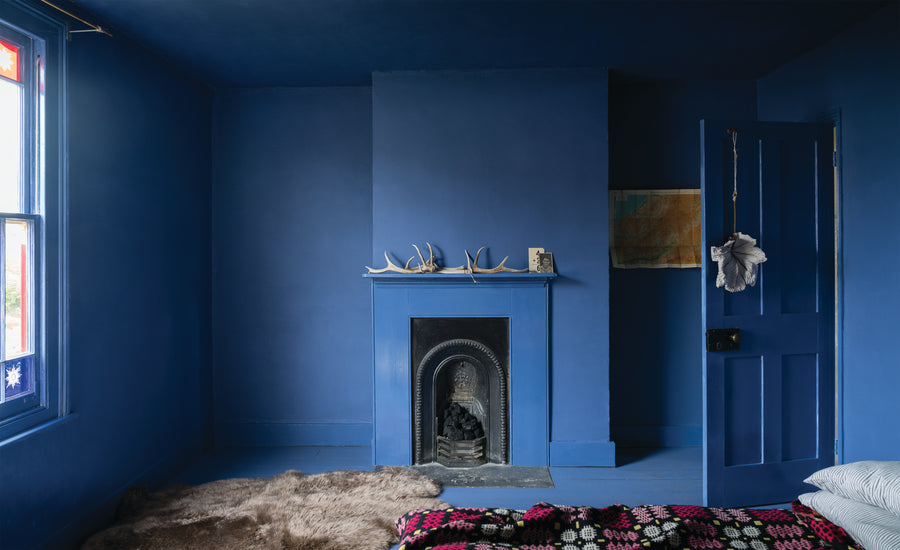Schlafzimmer mit Wänden, Kamin und Holzdetails im Farbton Pitch Blue No. 220 von Farrow & Ball